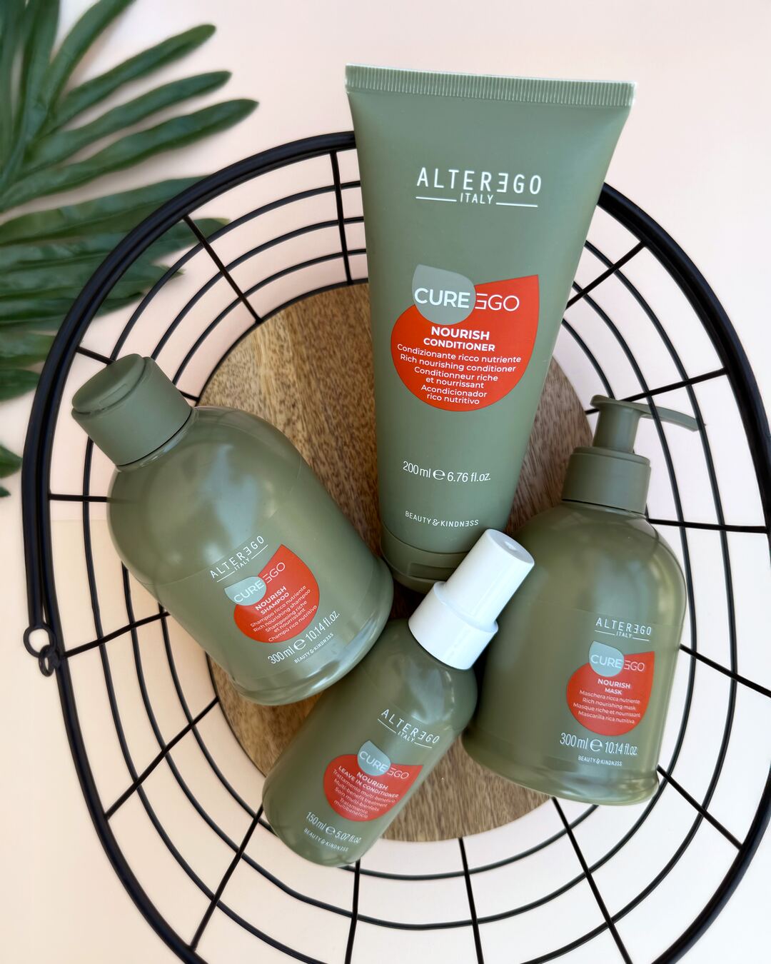 Alter Ego CurEgo Nourish hair care products arranged in wire basket with tropical leaves